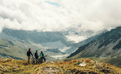 Drei E-Biker geniessen die Aussicht auf den Moirygletscher.