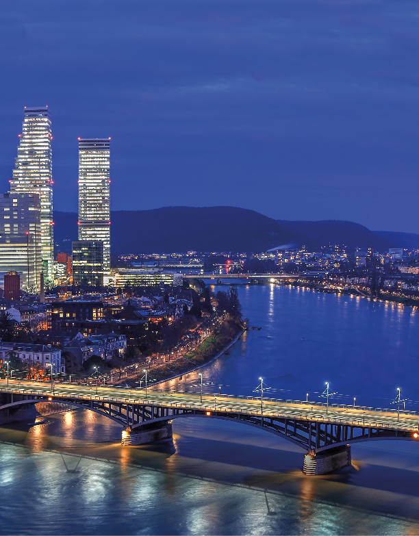 Night cityscape of the Swiss city Basel over the Rhine river with street lights and high rise buildings